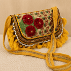 Decorative yellow banjara bag with floral patterns and tassels on a beige background
