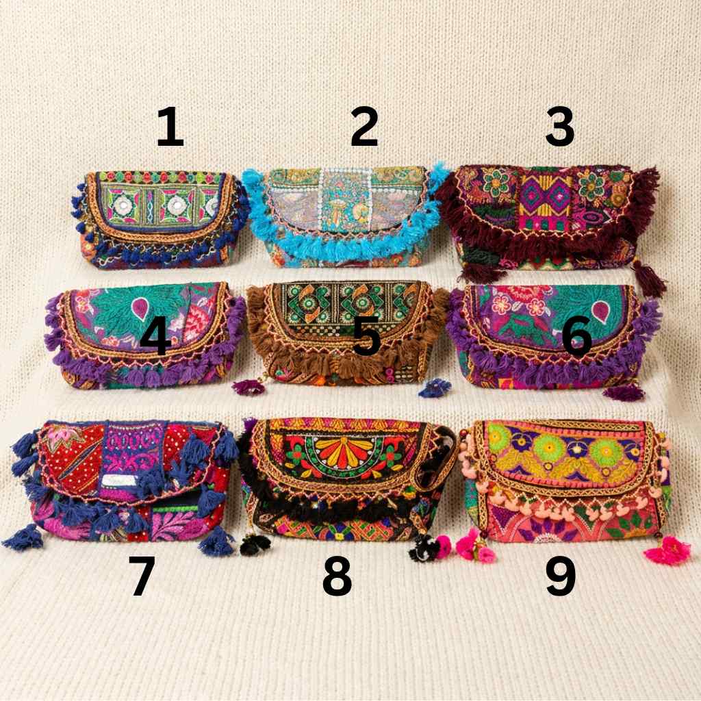 Nine colorful banjara sling bags with intricate designs and tassels on a beige background