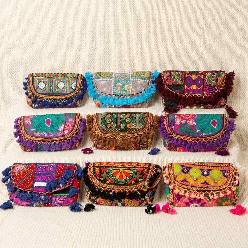 Set of colorful embroidered banjara sling bags on a beige background