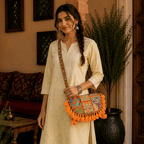 Woman holding a colorful orange banjara sling bagin a home setting