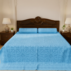 Blue patterned bedspread on a bed with wooden headboard and nightstands in a bedroom setting.