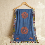 Blue embroidered dupatta on a wooden hanger against a beige wall.