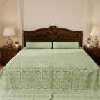 Bed with green patterned cover and wooden headboard in a bedroom setting.