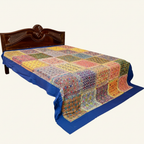 Colorful patchwork quilt on a bed with a wooden headboard against a white background