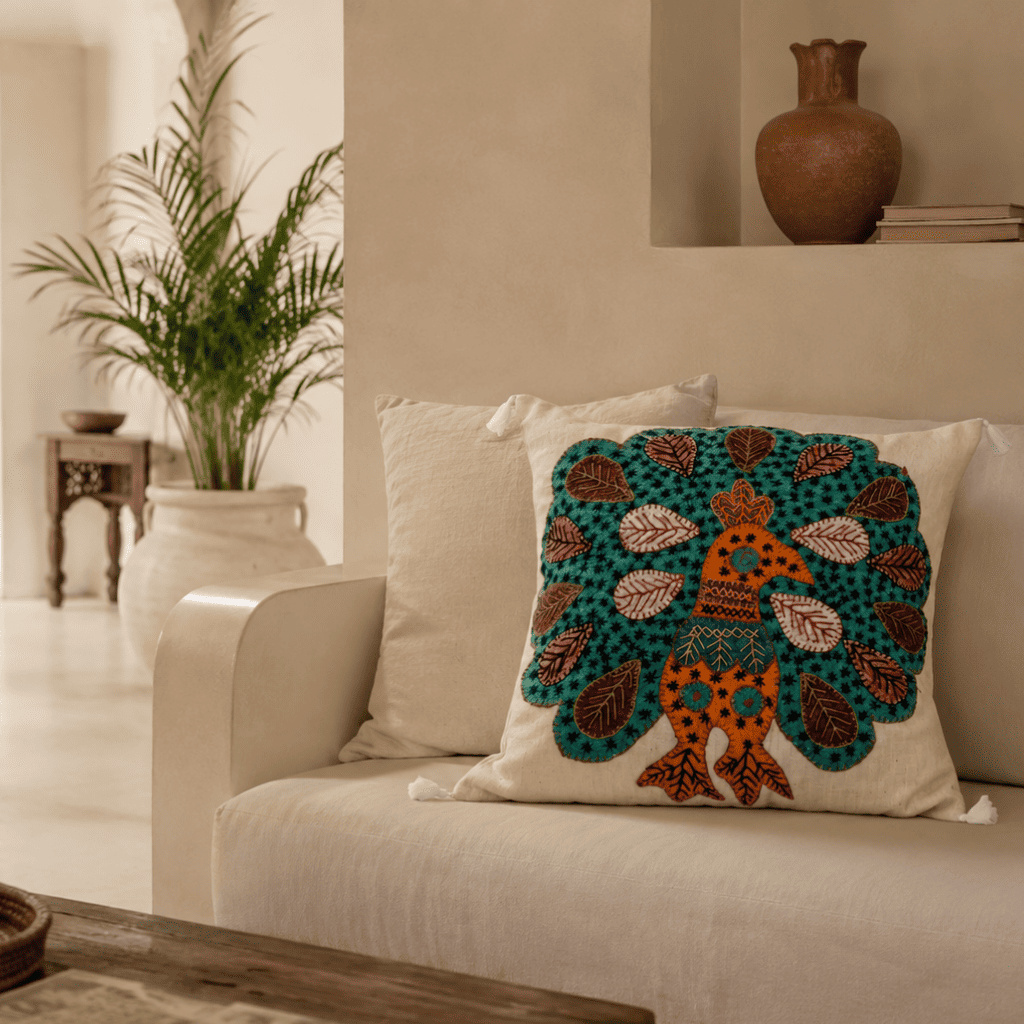 Decorative cushion cover with a colorful peacock design on a beige sofa in a living room setting.