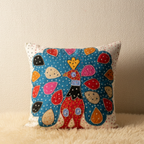 Decorative pillow with colorful peacock patchwork design on a beige background