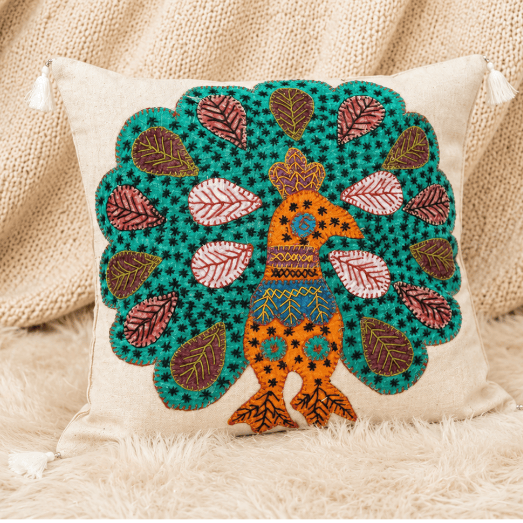 Decorative cushion cover with peacock design on a textured surface