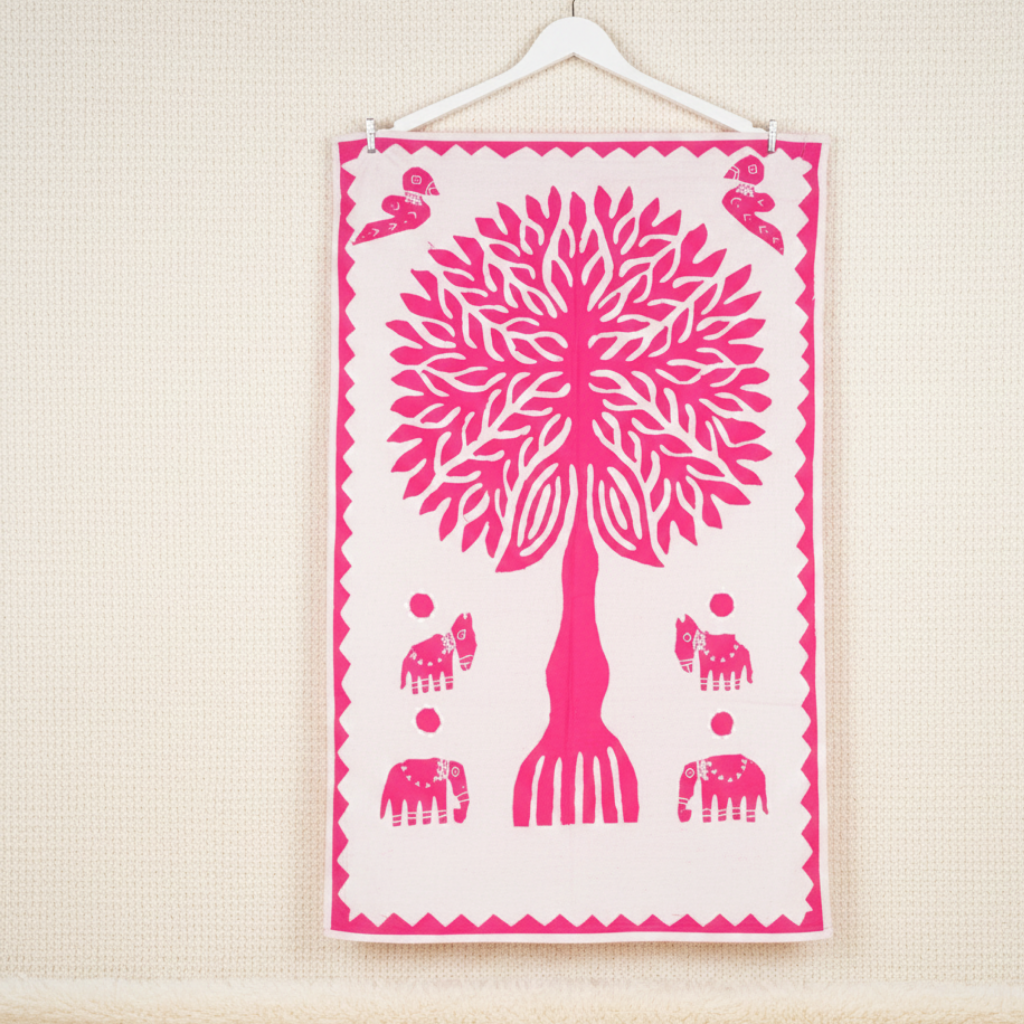 pink applique tree and animal motifs wall tapestry on a beige wall
