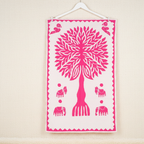 pink applique tree and animal motifs wall tapestry on a beige wall
