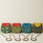 Four colorful handbags with patterned designs on a beige background