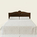 Bed with white quilt and wooden headboard on a beige background