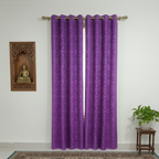 Purple curtain with grommets on a white wall with a small table and plant in the foreground.