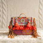 Colorful banjara handbag with floral patterns and tassels on a textured surface
