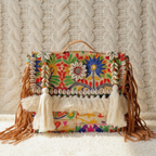 Colorful embroidered bohemian handbag with tassels on a textured surface