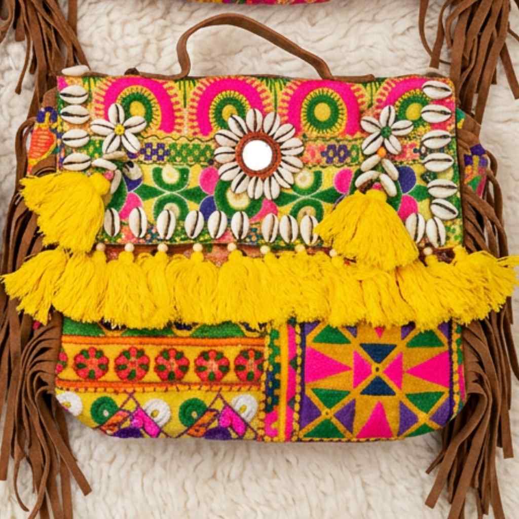 Colorful handbag with floral patterns, tassels, and embroidery on a textured surface.