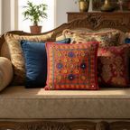 a red embroiderd  boho cushion cover with others on a sofa in a room setting