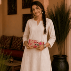 a girl in a white kurta carrying a red floral embroidered purse