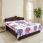 Decorative bedspread with applique tree patterns on a wooden bed in a bedroom setting.