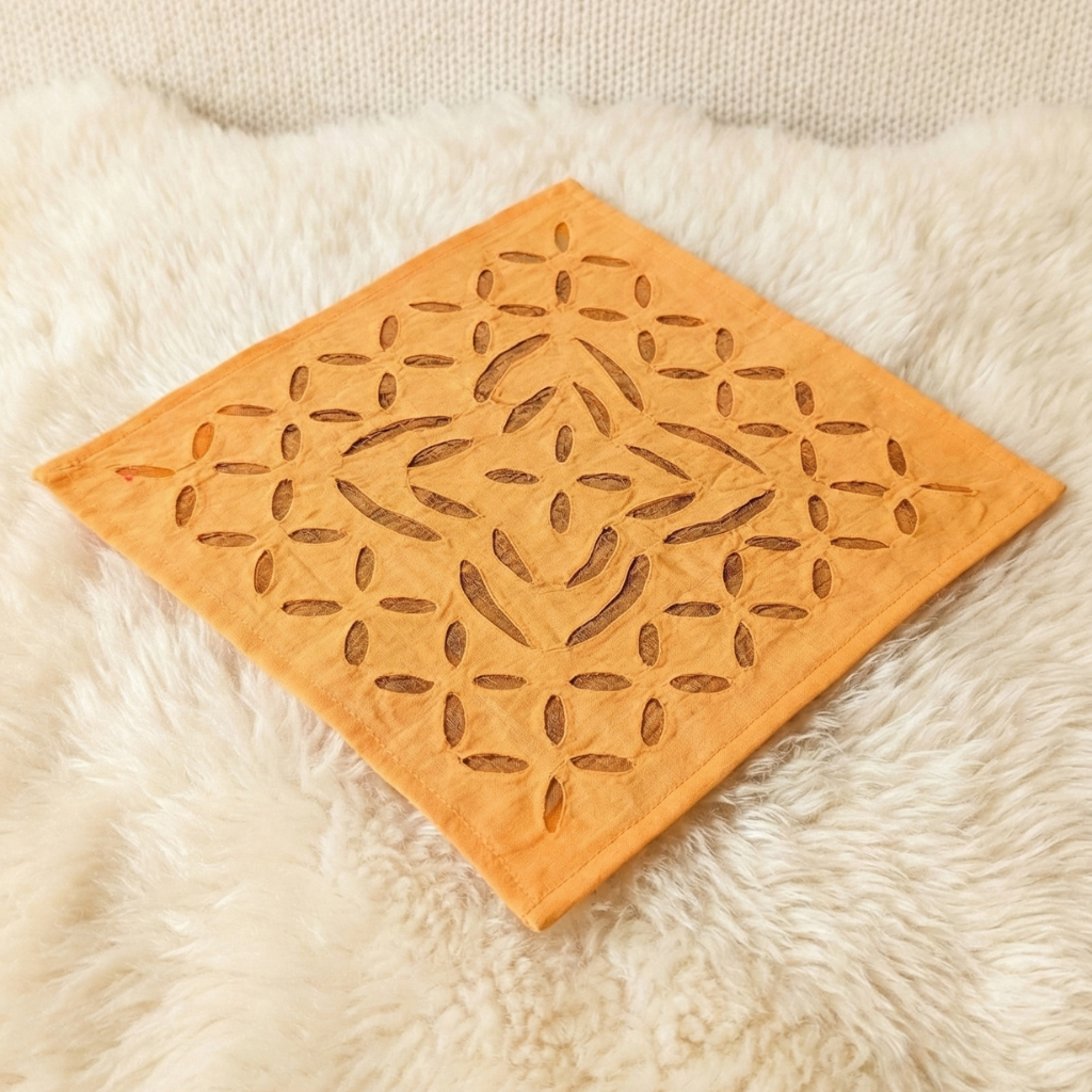 Decorative orange table napkin with a geometric pattern on a textured surface