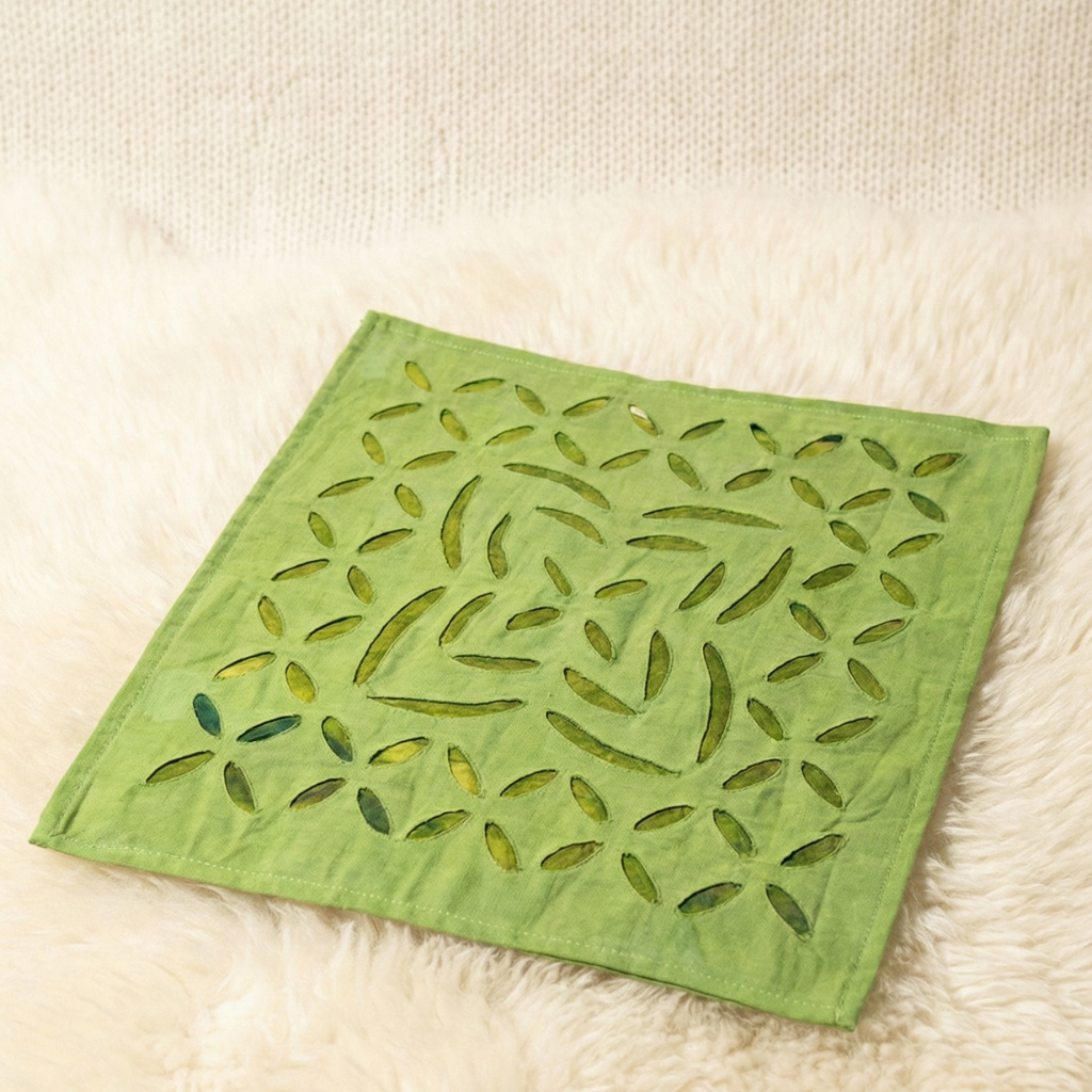 Green fabric square with leaf pattern on a beige surface