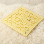 Yellow decorative mat with leaf pattern on a fluffy white surface