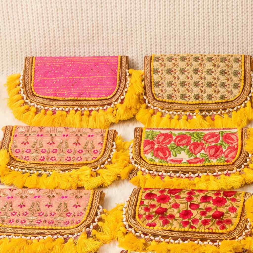 Set of colorful handbags with floral patterns and yellow tassels on a beige background