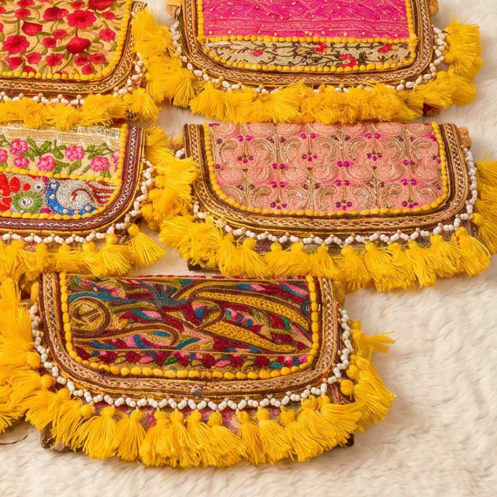 Colorful embroidered bags with yellow tassels on a white surface