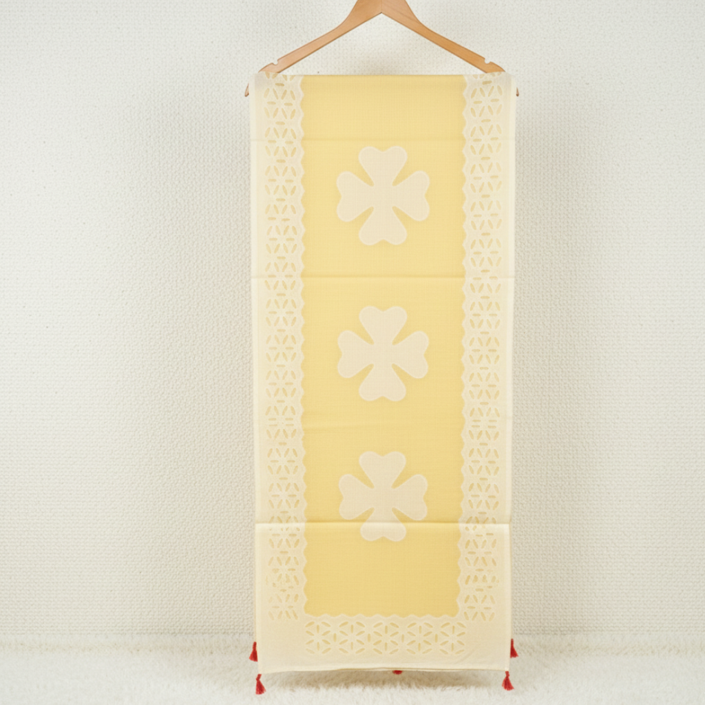 Yellow saree with floral patterns on a wooden hanger against a white background