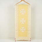 Yellow saree with floral patterns on a wooden hanger against a white background
