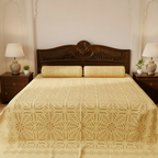 Bed with decorative yellow applique bedsheet and wooden headboard in a bedroom setting.