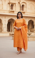 Woman in an orange traditional outfit standing in front of a historical building.
