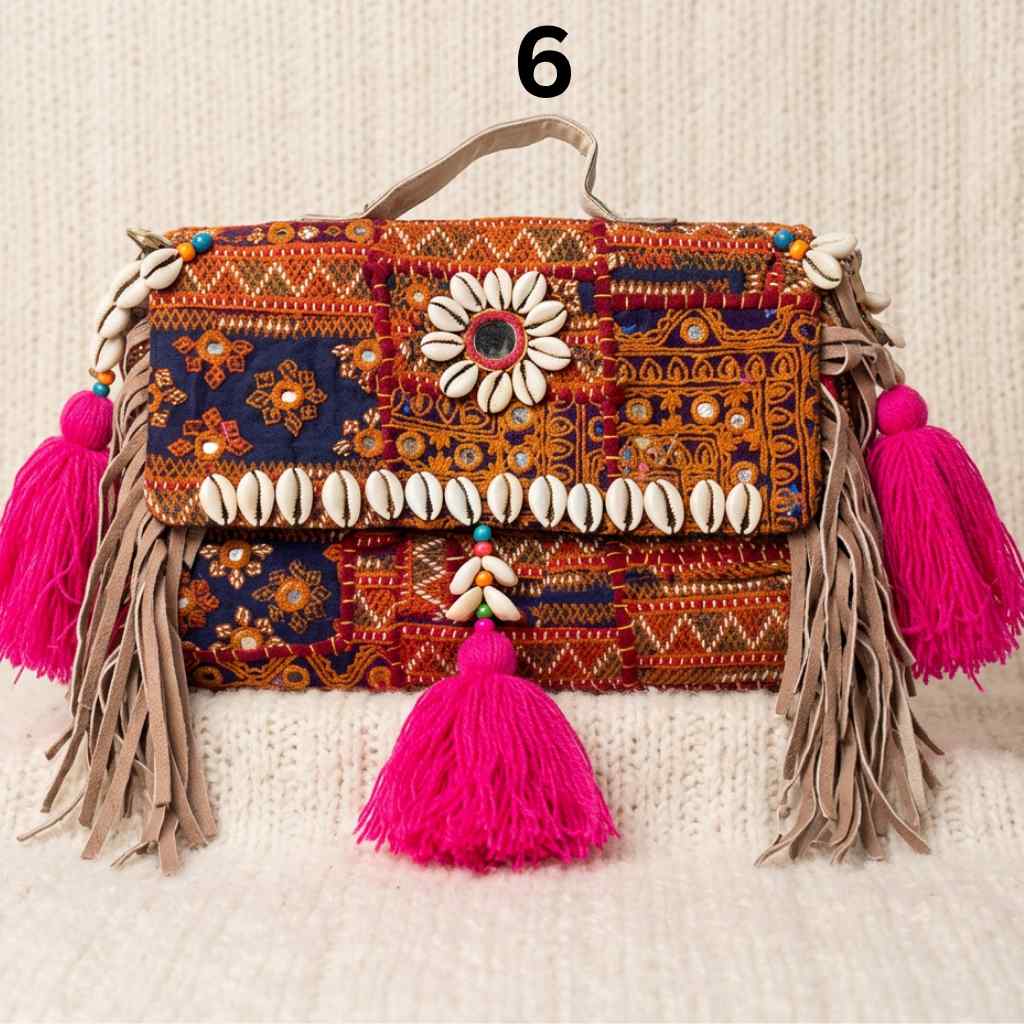 Colorful brown banjara handbag with tassels and shell decorations on a textured surface