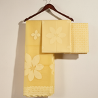 Yellow applique suit set fabric with floral patterns on a wooden hanger against a beige background
