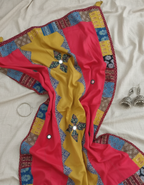 Red and yellow dupatta fabric with intricate patterns on a white background