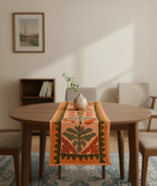 Dining room with a wooden table and an orange floral-patterned table runner.