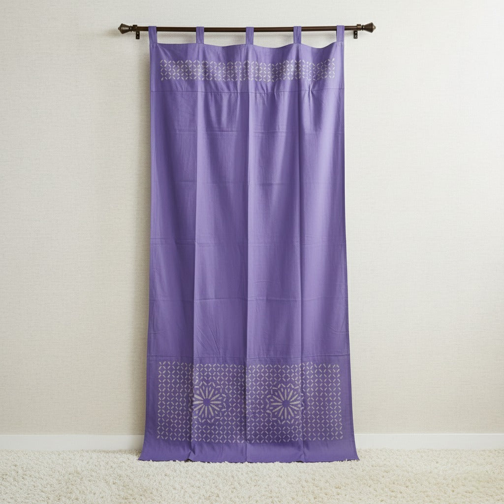 Purple curtain with geometric patterns on a wooden rod against a beige wall.