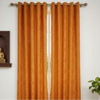 Orange curtain with a subtle pattern on a white wall with a small Buddha statue and plant.