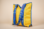 Yellow tote bag with blue trim and star patterns on a beige background